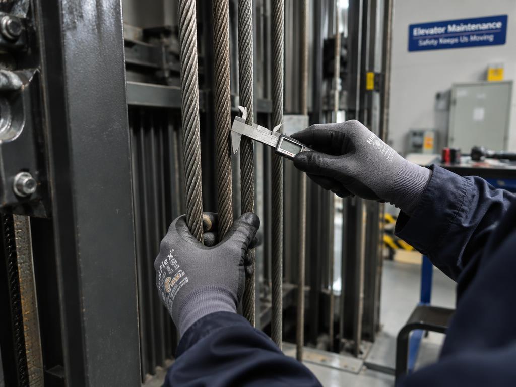 Tecnico che misura il diametro di una fune di trazione con calibro